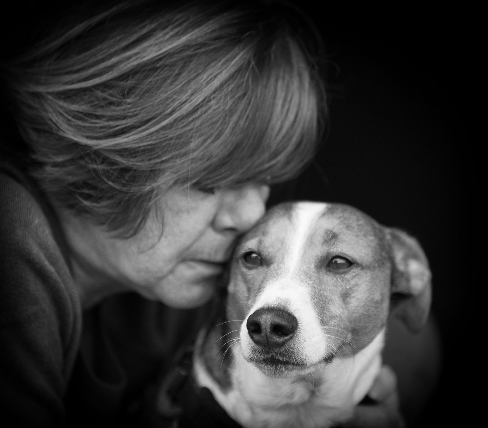 Dawn kissing Mylo, her tan-and-white Jack Russell, in a black-and-white photograph