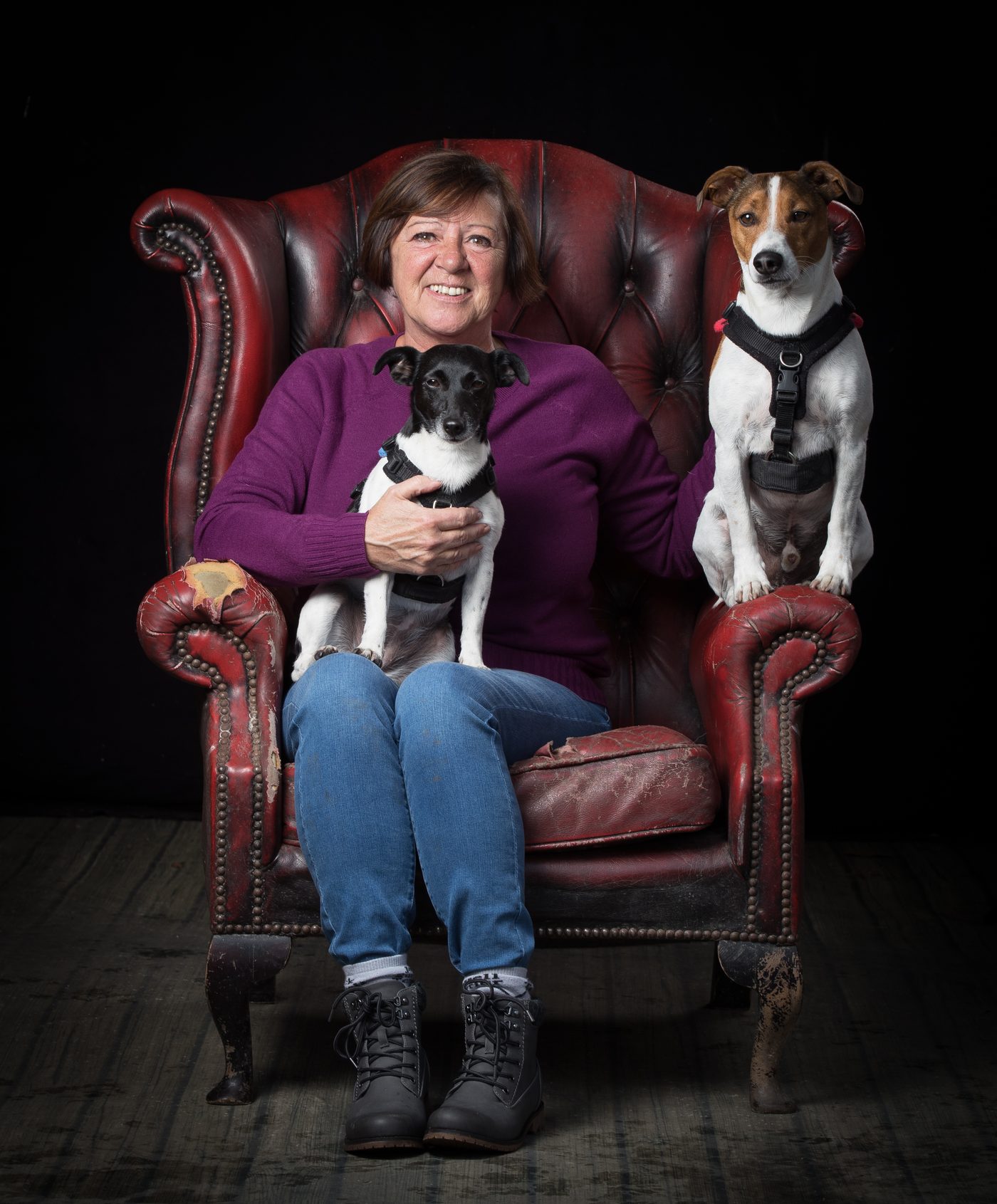 Dawn smiling in a red leather armchair, with Millie on her lap and Mylo on the arm beside her