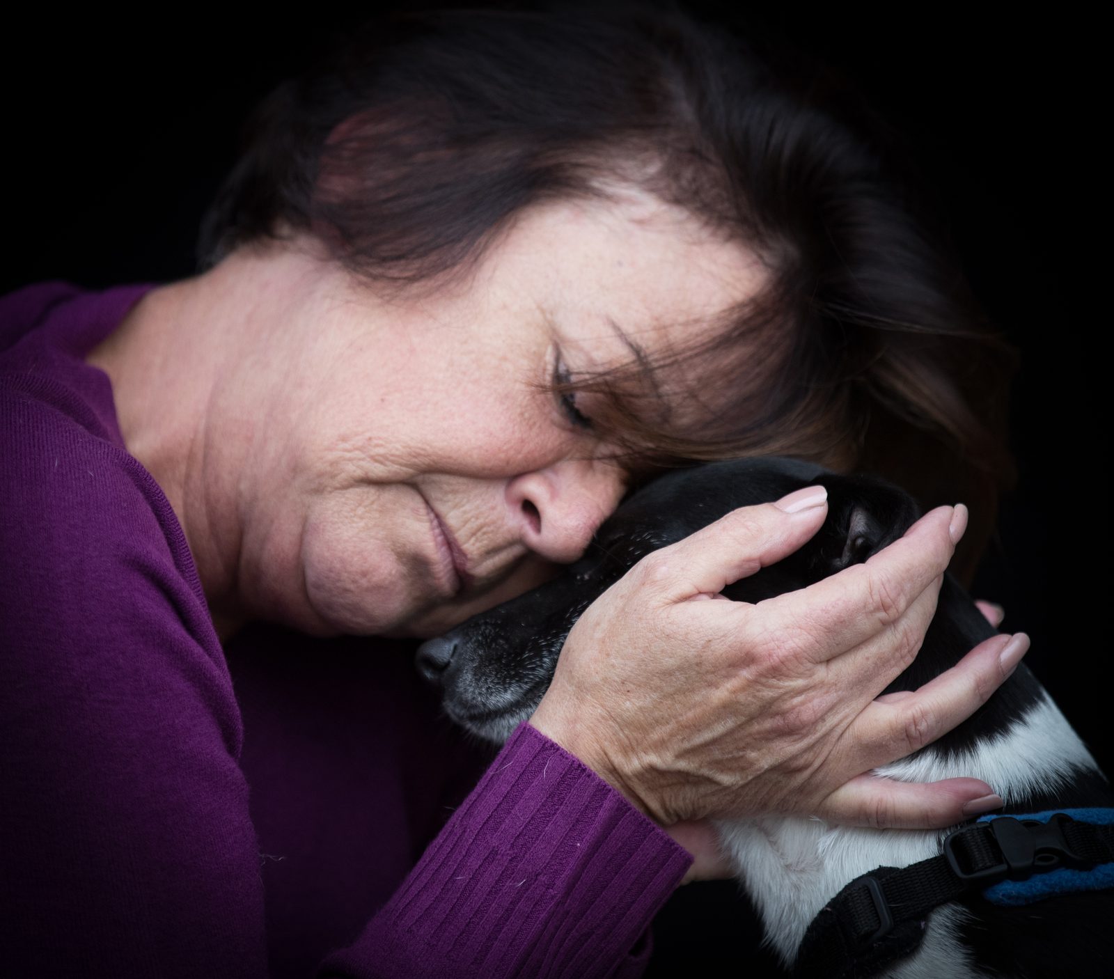 Dawn resting her forehead against Millie, her black-and-white Jack Russell