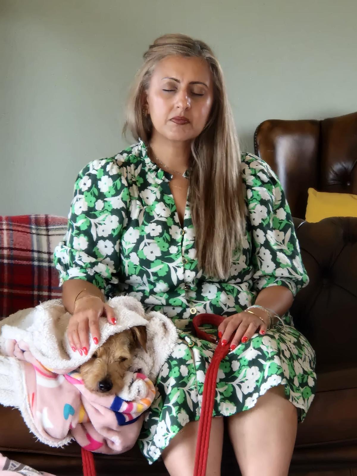 A guardian sitting quietly with her dog tucked beneath a blanket